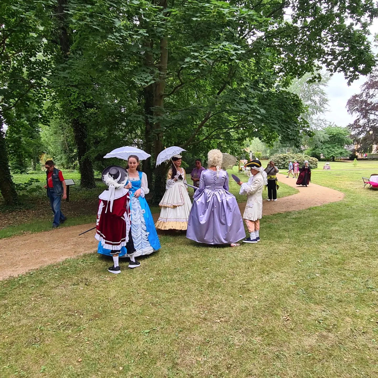 Barock gekleidete Menschen auf einem Weg im Gutspark