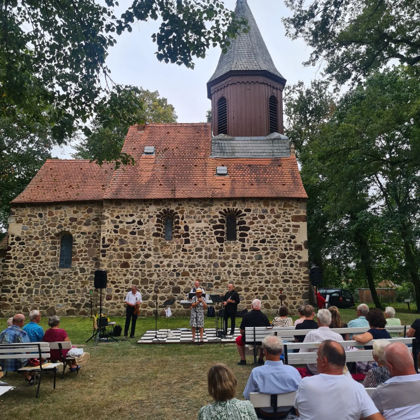 Musikerinnen und Musiker vor der historischen Feldsteinkirche
